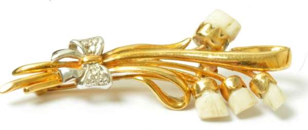 gold brooch set with four baby teeth and diamonds