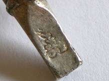 a small maker's mark on the mouthpiece of a baby rattle